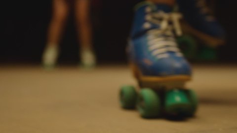 Female legs in roller blades, skating fast at the roller park on floor . Close-up legs of young women is professionally skating . Different kind of and colorful vintage  roller blades . Slow Motion