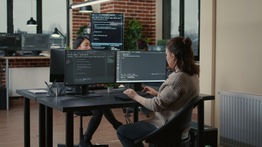 Junior developer putting laptop with source code on senior dev desk asking for opinion about database. Programer writing algorithm interrupted by colleague wanting help with fixing errors. Royalty-Free Stock Footage #1085228813