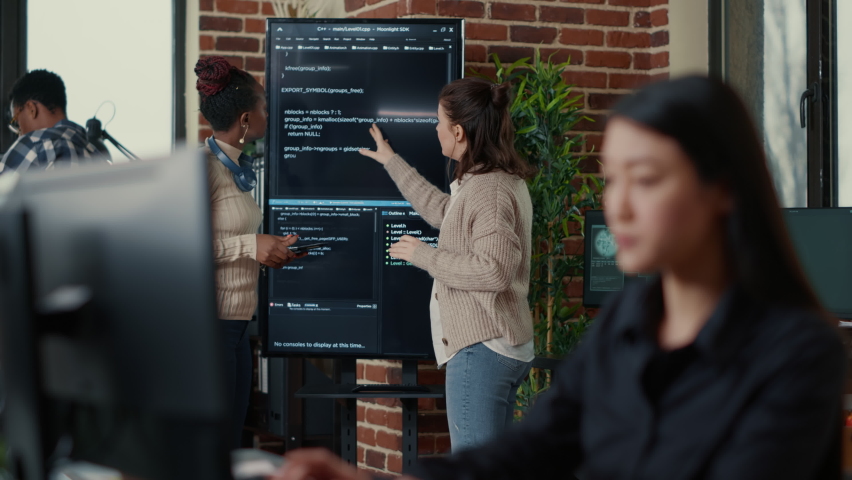 System engineers comparing source code on wall screen tv analyzing errors using digital tablet with focus switching to programer writing algorithm. Team of coders debugging machine learning data. Royalty-Free Stock Footage #1085228828