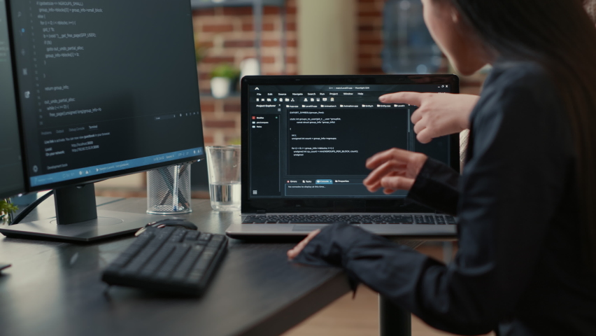 Team of programmers talking about algorithm running on laptop screen pointing at source code while sitting at desk. Software developers collaborating on data coding group project. Royalty-Free Stock Footage #1085228834