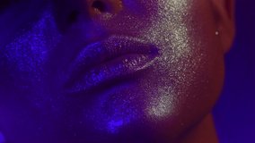 Fashion model golden make up woman kiss lips in bright sparkles, golden and blue colorful lights, beautiful girl lips, mouth. Trendy glowing gold skin make-up. Art design. Glitter metallic shine