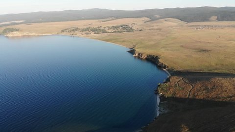 Aerial view of blue lake and hills. Baikal lake landscape view lake located in southern Siberia, Russia. View on the lake. Over crystal clear water. Drone's Eye View. Fresh water. Cinematic aeria