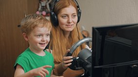 Boy with mother playing racing on game steering wheel