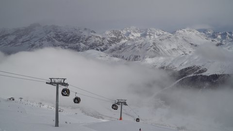 Livigno, Italy - December 29, 2021 - skiers and snowboarders with gondolas on a cloudy day