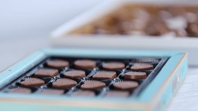 Woman take one chocolate from a box of different candies. Close-up shooting stock footage. slow motion