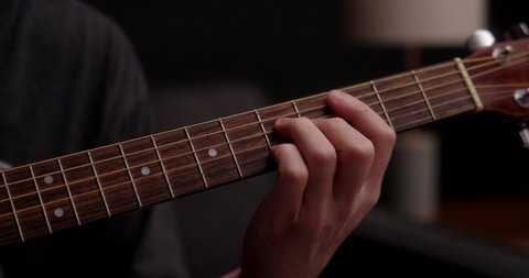 A musician playing an acoustic guitar in slow motion.