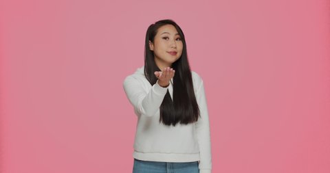 Come here, follow me. Friendly asian young girl calling with hands, beckon, inviting to communicate on pink background