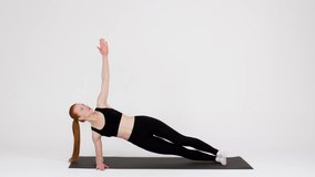 Athletic Young Woman Doing Side Plank Rotations Exercise While Training In Studio, Sporty Millennial Lady Making Endurance Workout, Exercising On Fitness Mat Over White Background, Slow Motion
