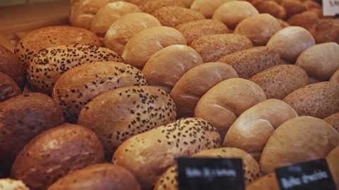Rows of Warm Freshly Baked Bread Rolls on Display in Bakery Stand at Local Grocery Store