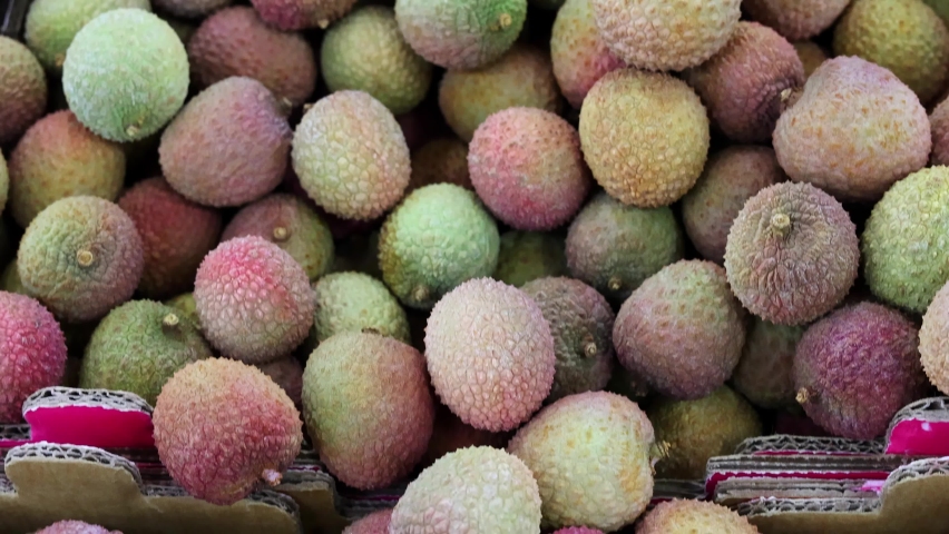 Pile of Lychee fruit, Litchi chinensis, for sale on a market stall.  Tilt shot Royalty-Free Stock Footage #1085252174
