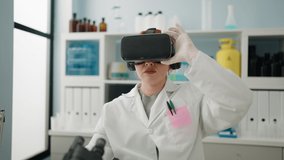 Young redhead woman wearing scientist uniform using virtual reality glasses working at laboratory
