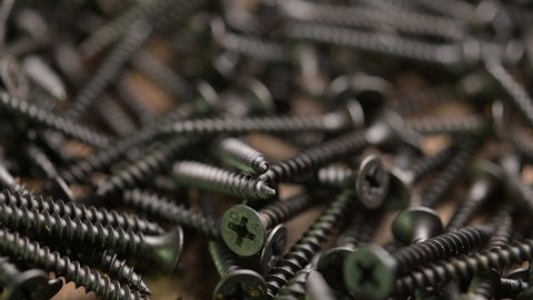 Selective focus. Close up shooting of parts of carpentry screws with cross head. Yellow screws on the table. Industry background 