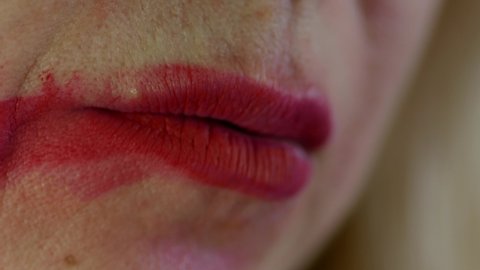 A woman is a victim of domestic violence experiencing stress. Close-up Woman smokes a cigarette with smeared lipstick on her face. The offended woman copes with the resentment. selective focus
