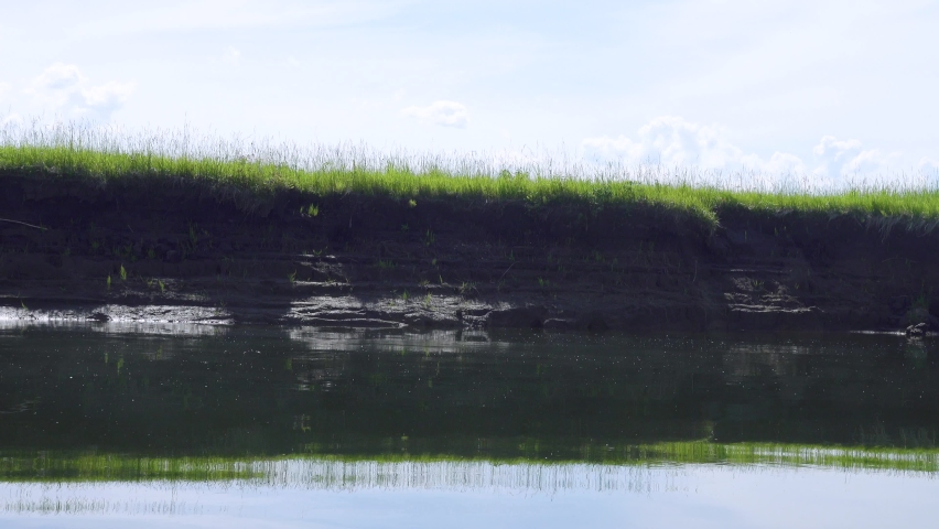 A washed-out river bank with bottomland meadow. Water erosion. Sail a boat along the shore (go with the flow), boat trip Royalty-Free Stock Footage #1085258984