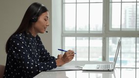 Asian young student use wireless earbuds to have online courses and searching information via laptop computer