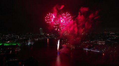 Aerial drone spectacular night video of firework show with dazzling colours glowing over river Thames to celebrate new year's eve, London, United Kingdom