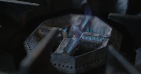 Kitchen burner turning on. Stovetop burner igniting into a blue cooking flame. Natural gas inflammation, close up. slow motion shot of flame kitchen stove. restaurant stove. blue fire falmes