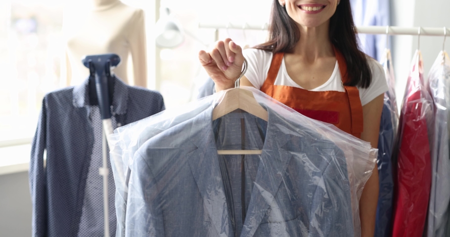 Smiling receptionist at dry cleaning hands over clothes to client | Shutterstock HD Video #1085276213
