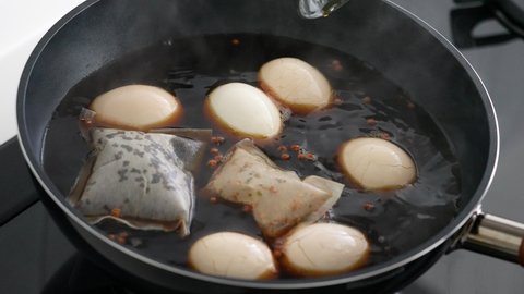 Cooking and boiling traditional Taiwanese famous food tea eggs with black tea leaf and soy sauce at home.