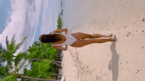 Vertical video. Mauritius, Indian ocean beach, woman relax near palms trees. Beauty girl at sea sand coast rest in summer sunny day. Epic tropical resort. Cinematic plot shot in 4K