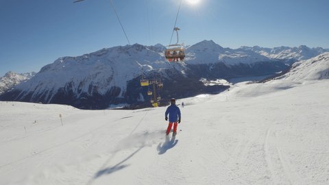 Two skiers descending slope in winter. Tracking shot of people skiing on a sunny bright day in the Alps. Slow motion 