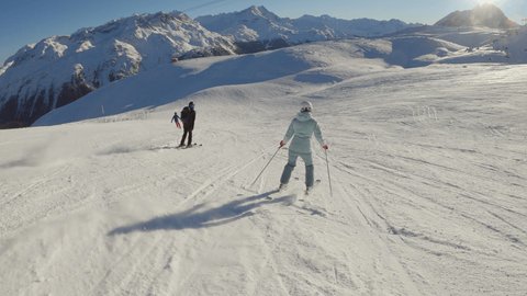 Group of skiers descending slope in winter. Tracking shot of people skiing on a sunny bright day in the Alps.