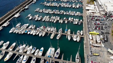 Aerial footage of the beautiful Boats a Boat Harbour Marina and pier taken in Lanzarote in Spain one of the Canary islands, showing all kinds of sailing boats in the calm ocean at Marina Puerto Calero