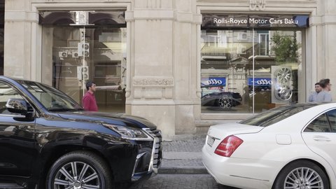Baku Azerbaijan - May 2, 2019: Rolls Royce showroom signage on the showcase of the Baku representative in central part of the city with pedestrians walking near luxury expensive cars