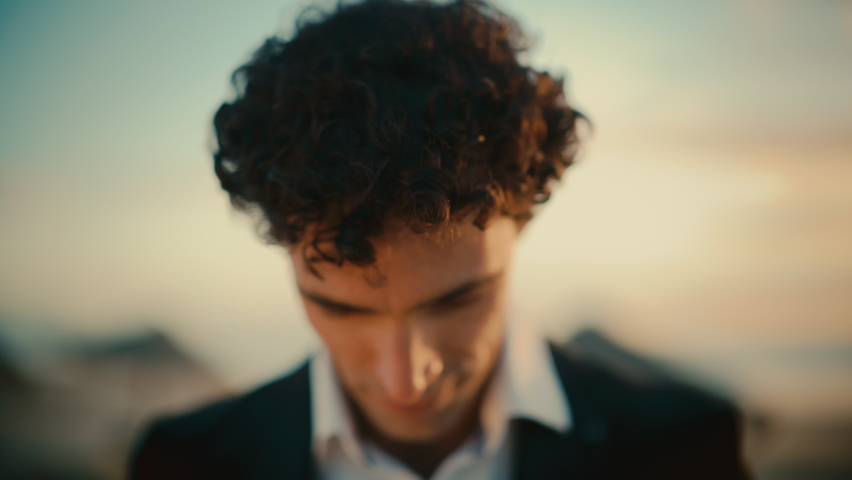 Close Up Portrait of a Happy Young Adult Male with Curly Hair and Brown Eyes Posing for Camera. Handsome Multiethnic Caucasian Male in a Suit Charmingly Smiling. Warm Color Edit. Royalty-Free Stock Footage #1085290433