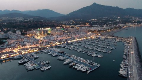 Aerial drone panoramic view of Puerto Banus Marbella marina luxury port at dusk	