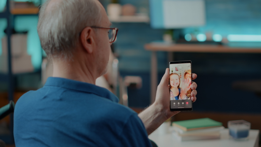 Retired man talking to family on online videoconference, holding mobile phone for remote communication. Older person using internet teleconference on smartphone to chat with relatives. Royalty-Free Stock Footage #1085297630