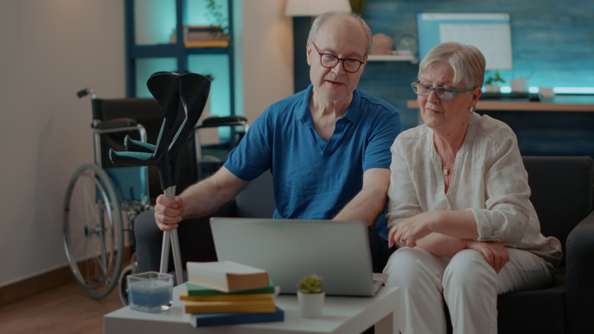 Grandparents waving at video conference call webcam, using laptop to chat. Man with crutches and woman talking on online remote teleconference. Old people having conversation on internet Royalty-Free Stock Footage #1085297699