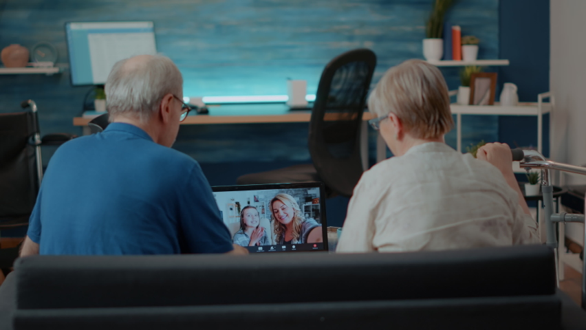Elder couple using online teleconference to chat with relatives on laptop computer. Senior people talking to daughter and little child on videoconference call for remote communication. Royalty-Free Stock Footage #1085297771