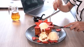 Working woman eating dessert, Honey toast with ice cream and working on grey laptop in coffee shop. Female enjoy life work outside company as remote working.