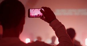 Man is taking Video or Pictures with Smartphone of live Music Concert or Festival Event. Blogging or Nightlife concept. 4K handheld shot in slow motion