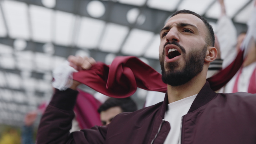 Young arabian guy with scarf on neck supporting national team during football match on big stadium. Concept of sport, human emotions, entertainment. | Shutterstock HD Video #1085305490