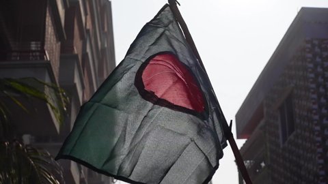 The national flag of Bangladesh is flying in the sky. The flag of Bangladesh is made of a center red circle in green. Close Up View of the national flag of Bangladesh made of Silk fabric. Slow motion.