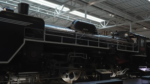 Nagoya.Japan-October 31.2019: A vintage locomotive with a Japanese flag at the Nagoya railway museum. Steam engine. Vintage transportation technology. Black. Camera slowly turning left.