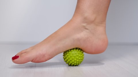 foot step on massage ball to relieve Plantar fasciitis or heel pain. woman with red pedicure massaging trigger points on her foot