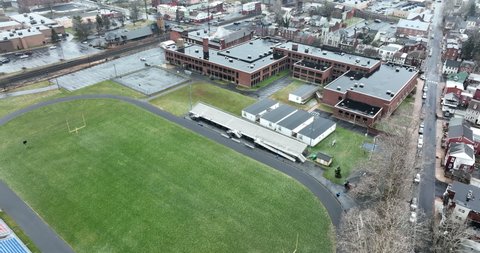 Rear view of school building with temporary modular trailer buildings for extra classroom space. Athletic field. American USA urban city on winter rainy day.