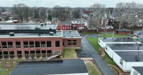Side truck shot of public school and temporary modular classroom buildings. Aerial view in urban American city.