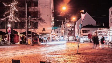 4k dynamic Time Lapse of Ostertorsteinweg at the entrance of Viertel. Night traffic of trams, people, and cars with light trails. Busy evening vibes in illuminated street, 2022-01-02 Bremen Germany