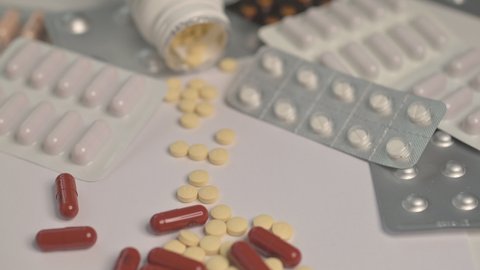 Selective focus. Close up shooting of different pills falling on table with blisters with medicine.Tablets and pills. 