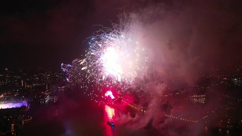Aerial drone spectacular night video of fireworks show with dazzling colours glowing over river Thames to celebrate new year's eve 2022, London, United Kingdom