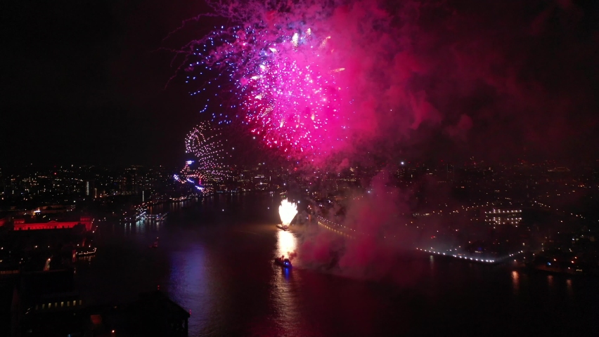 Aerial drone spectacular night video of fireworks show with dazzling colours glowing over river Thames to celebrate new year's eve 2022, London, United Kingdom