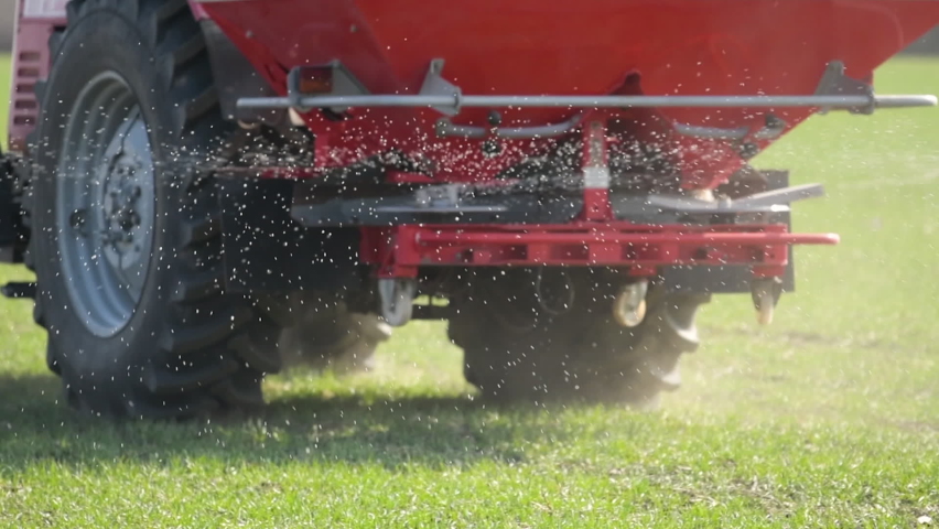 Agricultural tractor is fertilizing wheat crop field with NPK fertilizer nutrients, slow motion handheld footage | Shutterstock HD Video #1085320586