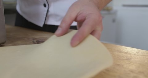 Close up shot chef kneading dough on wooden surface.