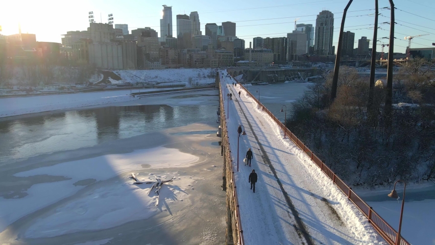 people at stone arch bridge crossing the mississippi river in Minneapolis downtown view winter afternoon