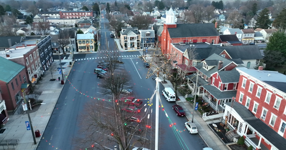 Winter scene in Small Town America. Aerial establishing shot of homes and church with Christmas lights and star. Drone orbit.