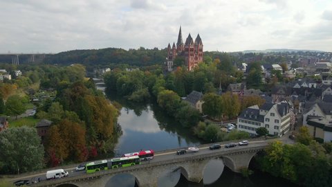 Reveal shot of hill with Limburg Cathedral at river Lahn with traffic on old stone bridge